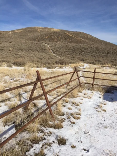 Steel jack fence running across a sagebrush slope in rural Idaho