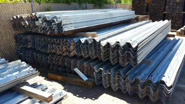 Bundles of used highway guardrail stacked at the yard